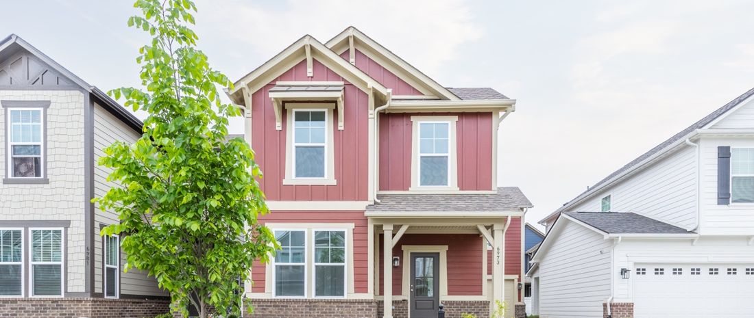 The Bennett family's two-storey home, a red board-and-batten house with a covered front porch, on a quiet residential street